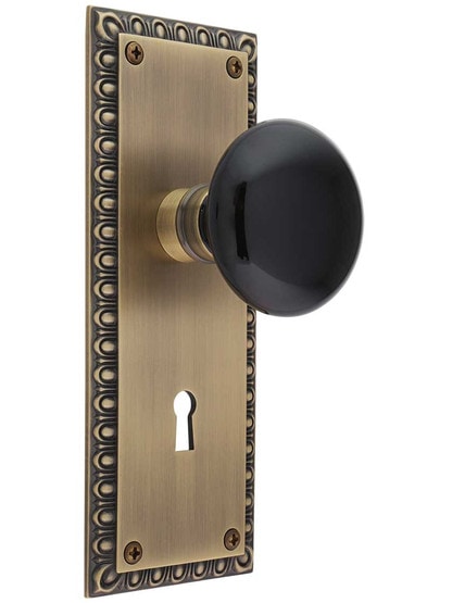 Ovolo Mortise-Lock Set with Black Porcelain Knobs in Antique Brass.